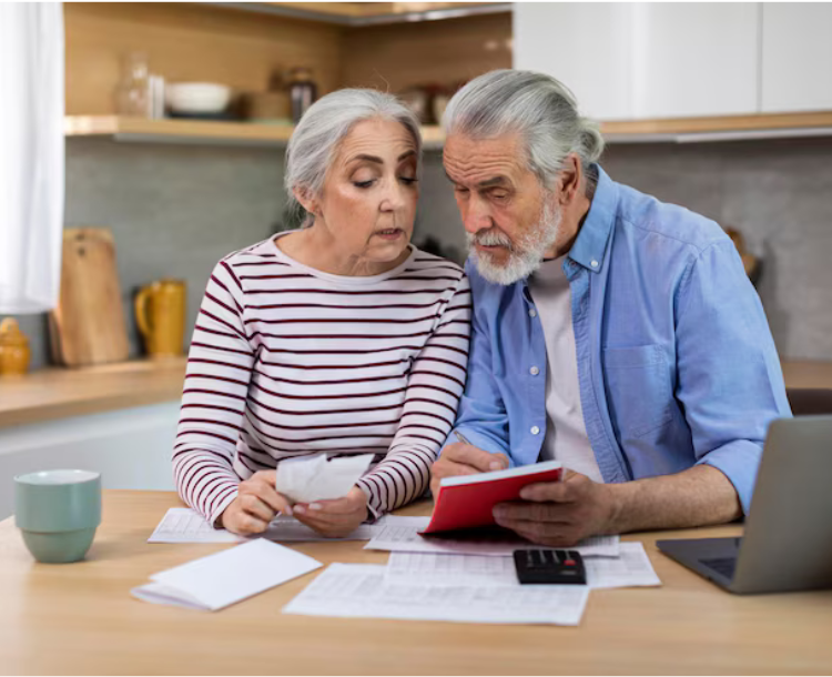 Elderly couple reviewing finances and planning for retirement at home