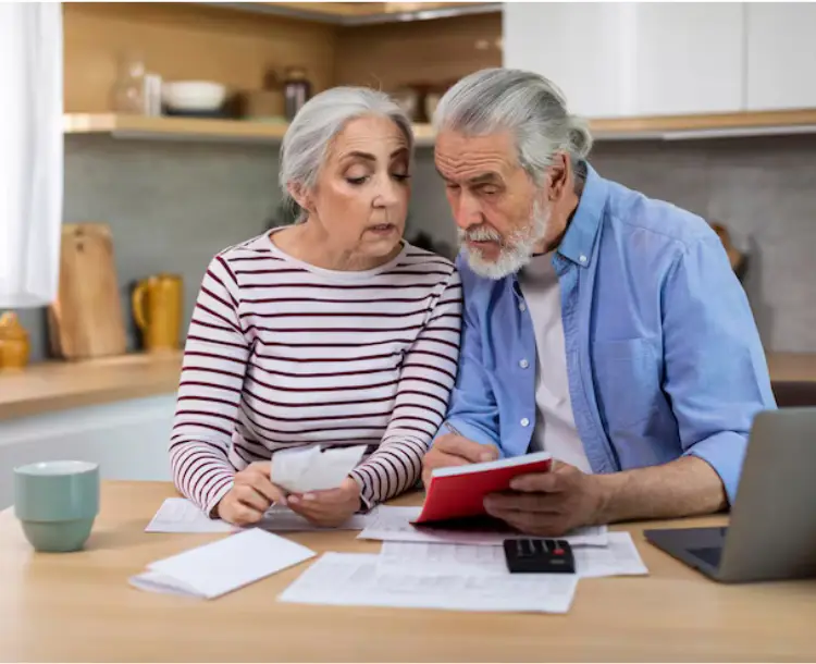 Elderly couple reviewing finances and planning for retirement at home