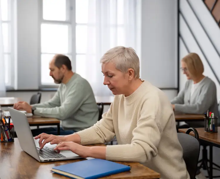 Senior man learning to use a laptop in a digital skills class