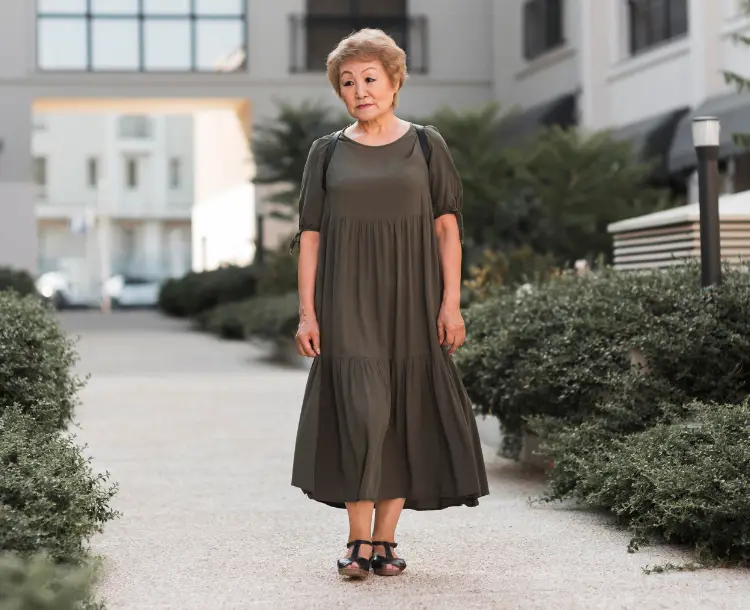 Elderly woman standing confidently outdoors, reflecting the strength of women and aging