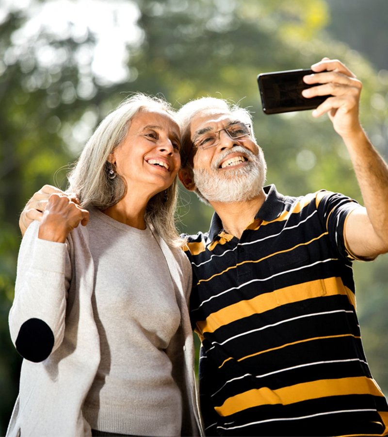 Happy elderly couple taking a selfie on an Android phone, showcasing technology for senior safety and digital connection